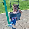 Delanie is registered to the contest to win money with this photo: child, toddler, swing, playground, outdoor, grass, chain_link_fence, curly_hair, blue_jeans, sneakers, sunlight, shadow, smiling, seat, plastic_swing, metal_chains, pavement, casual_clothing, greenery, fun