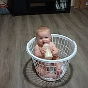Braylynn Wright joined the competition — help win amazing prizes! baby, infant, laundry_basket, bottle, floor, wooden_floor, smiling, indoors, television, cabinet, furniture, milk, child, cute, sitting, home, room, object, happy, person