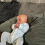 Renson joined the competition — help win amazing prizes! baby, infant, couch, pillow, onesie, striped_clothing, indoor, soft_furniture, seated, portrait, young_child, curious, cozy, head, hands, face, relaxing, home, child, comfort