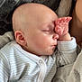 baby, sleeping, hand, face, onesie, striped_clothing, blanket, soft_texture, cozy, infant, peaceful, closeup, skin, ear, nap, child, person, resting, indoors, portrait
