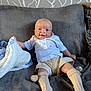 Renson is registered to the contest to win money with this photo: baby, infant, smiling, couch, blanket, socks, shorts, white_shirt, happy, indoor, person, face, head, cozy, soft, plush, home, furniture, patterned_wallpaper, relaxed