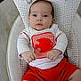 baby, infant, child, face, blue_eyes, white_shirt, red_shorts, fish_graphic, cushioned_seat, plush_toy, soft_fabric, indoor, portrait, cute, small_hands, sitting, curious, young, clothing, person