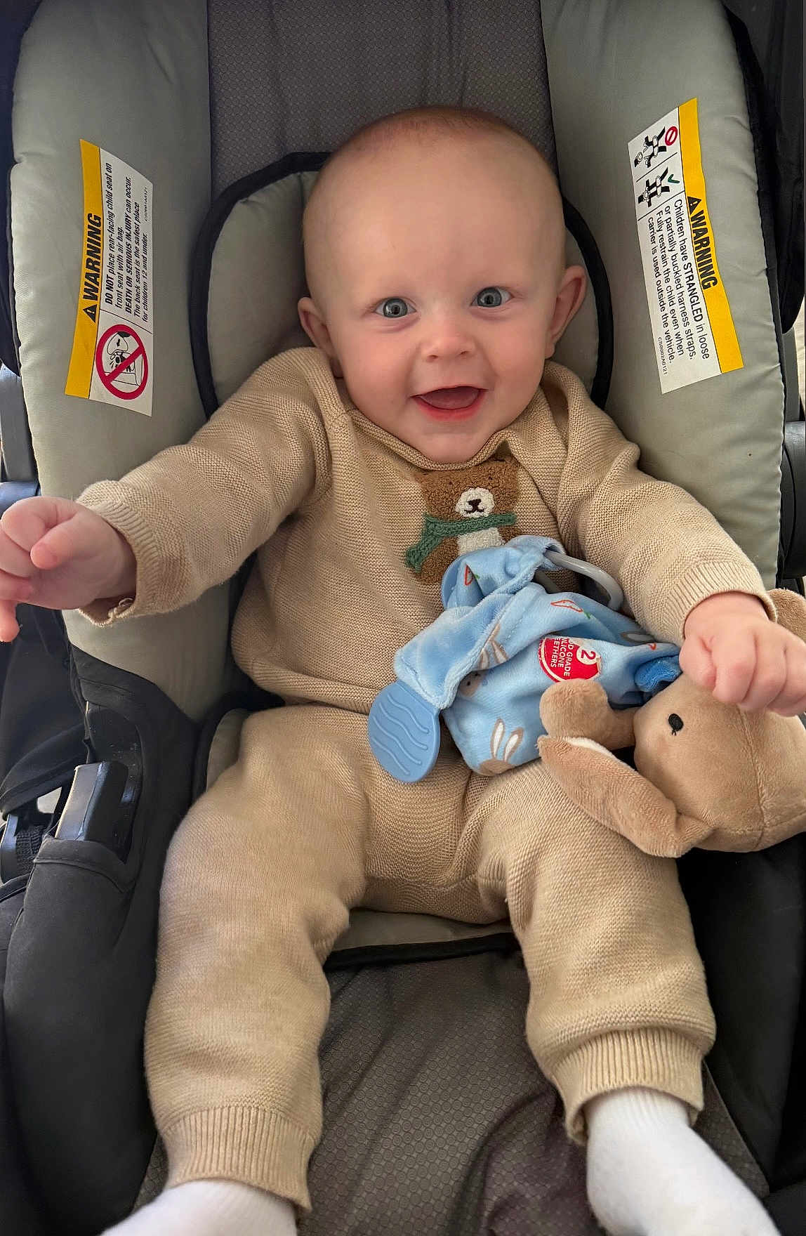 Dillinger joined the competition — help win amazing prizes! baby, child, car_seat, plush_toy, toy, knitwear, beige_clothing, happy, smiling, person, infant, cute, indoor, seat, fabric, head, face, hands, feet, comfort