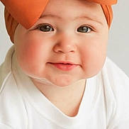 Emberly is registered to the contest to win money with this photo: baby, child, bow, headband, orange, white_clothing, crawling, face, cheeks, eyes, smile, infant, cute, portrait, headwear, baby_girl, expression, indoors, soft_light, closeup