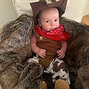 Beau Ryan joined the competition — help win amazing prizes! baby, cowboy, hat, bandana, fur_blanket, infant, clothing, costume, portrait, cute, child, person, indoors, sitting, cow_print, brown, red, soft_texture, warm, expression