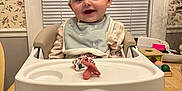 Amelia joined the competition — help win amazing prizes! baby, bib, blinds, child, cozy, face, floral_wallpaper, footwear, happy, high_chair, home, indoor, pacifier, pajamas, person, smiling, table, toy, window, wooden_table