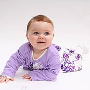 Evelyne is registered to the contest to win money with this photo: baby, blue_eyes, child, clothing, crawling, cute, expression, face, floral_dress, hands, happy, infant, lavender_cardigan, person, portrait, smiling, studio_photo, toddler, white_background, young_child