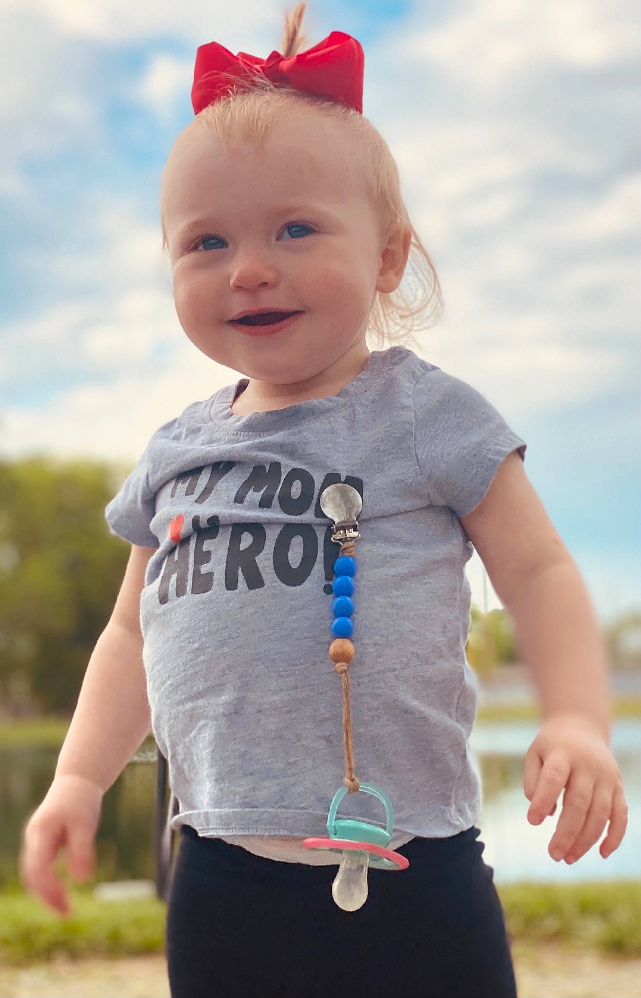 Hazley is registered to the contest to win money with this photo: baby_toddler_clothing, child, cloud, cool, costume_hat, eye, face, facial_expression, fun, gesture, grass, happy, joy, person, pink, sky, sleeve, smile, standing, t_shirt