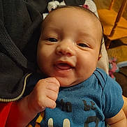 Elijah is registered to the contest to win money with this photo: baby, child, smile, blue_shirt, face, hand, indoor, furniture, toy, person, joyful, happy, closeup, infant, cute, skin, expression, sitting, holding, casual