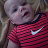 Wesson James is registered to the contest to win money with this photo: baby, infant, face, person, clothing, striped_shirt, nike_logo, blanket, texture, lying_down, cute, portrait, young_child, skin, head, eyes, mouth, arm, indoor, casual