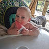 Wesson James is registered to the contest to win money with this photo: baby, high_chair, popsicle, child, dog, porch, wooden_beams, outdoor, greenery, sunlight, face, chewing, curious, plastic_container, table, blanket, pet, summer, infant, closeup