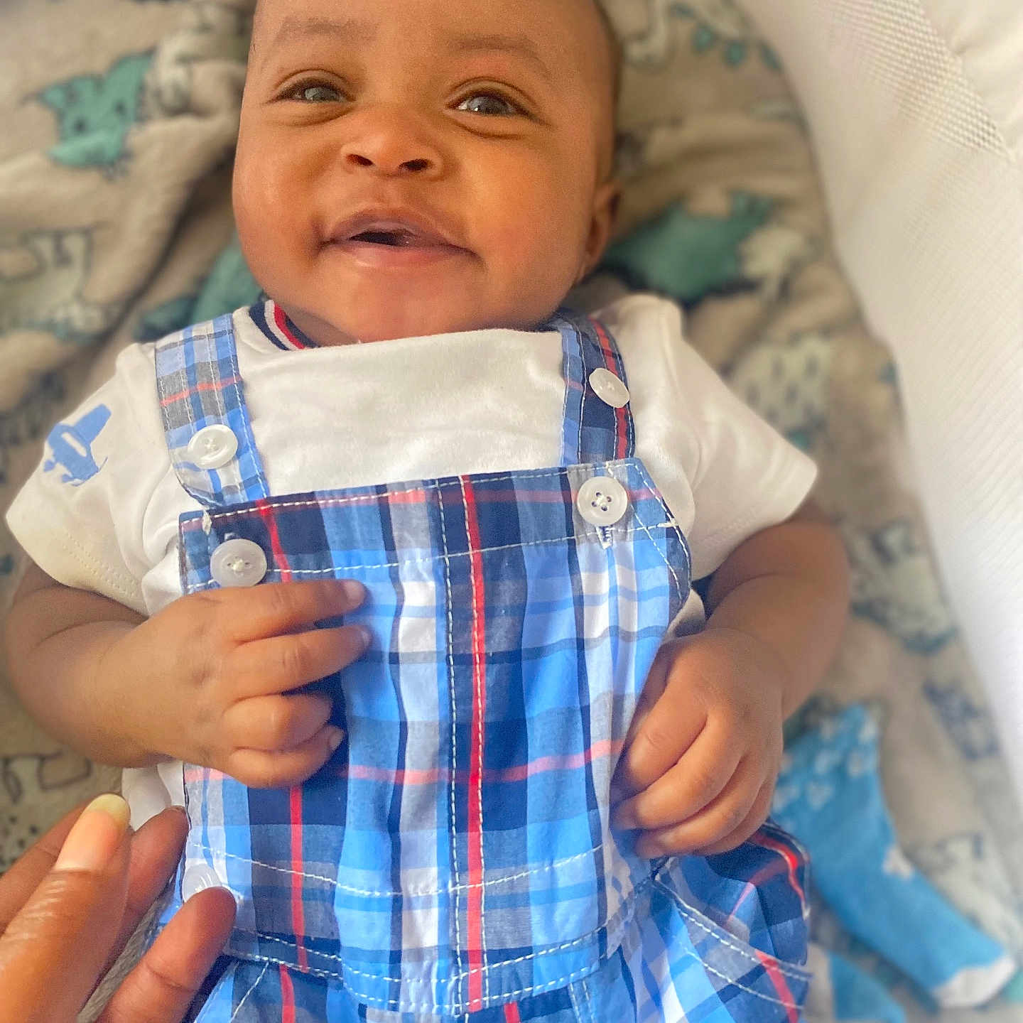 Maleek is registered to the contest to win money with this photo: baby, blanket, blue_plaid, child, closeup, cozy, cute, face, fingers, hand, happy, indoor, infant, lying_down, overalls, patterned, portrait, smile, soft_toys, white_shirt