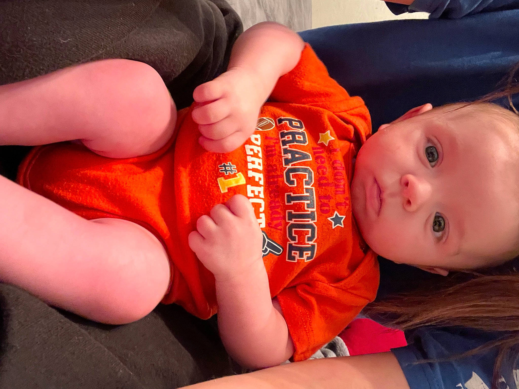 Cooper is registered to the contest to win money with this photo: arm, baby, baby_toddler_clothing, cheek, comfort, ear, elbow, finger, gesture, hand, head, human_body, joint, mouth, nose, orange, person, skin, sleeve, thumb