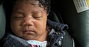 Saraii is registered to the contest to win money with this photo: baby, black_hair, button, car_seat, child, child_safety, close_up, cute, denim_jacket, fabric, floral_clothing, indoors, infant, peaceful, portrait, resting, seat, seat_belt, sleeping, young_child