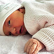 Elise participe au concours pour gagner de l'argent avec cette photo : newborn, baby, infant, knitted_clothing, white_cap, lying_down, fluffy_blanket, close_up, hand, skin, face, sleepy, cute, soft_texture, warm, resting, portrait, cozy, child, baby_clothes