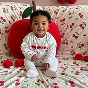 Loëlya a rejoint le concours — aidez-le/la à gagner de superbes lots ! baby, child, smiling, sitting, plush_toy, cherry_pattern, decorations, indoor, cute, white_clothing, face, portrait, soft_toys, background, home_decor, infant, happy, playful, cozy, colorful