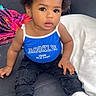 toddler, child, baby, blue_bow, blue_tank_top, brooklyn, sitting, couch, blanket, curly_hair, white_shoes, casual_clothing, indoor, portrait, cute, small_hands, expressive_eyes, fashion, comfortable, colorful