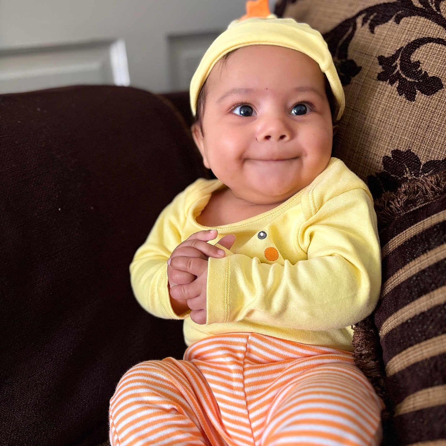 Malaki is registered to the contest to win money with this photo: baby, bodypart, cap, clothing, couch, cushion, face, finger, furniture, hand, happy, hat, head, homedecor, pants, person, photography, portrait, sitting, smile