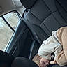 child, sleeping, car_interior, backseat, leather_seat, window, clothing, young, curled_up, peaceful, indoor, seat, headrest, casual, relaxed, person, transportation, travel, daytime, cozy