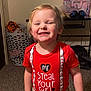 Carlisle joined the competition — help win amazing prizes! child, smiling, red_shirt, text_on_clothing, indoor, carpet, laundry_basket, headphones, bag, table, blond_hair, happy, standing, casual_clothing, toddler, person, face, cheeky_text, home, room