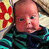 baby, infant, face, eyes, expression, clothing, striped, blanket, crochet, flower, red, yellow, blue, indoor, bed, bedroom, soft, skin, person, cute