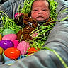 baby, infant, face, eyes, cushion, clothing, green_grass, easter_eggs, colorful, plastic_eggs, pink, purple, orange, blue, brown_jacket, indoor, portrait, cute, decorative_grass, newborn