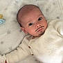 baby, infant, face, mustache, goatee, white_sweater, blanket, lying_down, cute, indoors, child, portrait, soft_texture, buttoned_clothing, young_child, human, skin, head, eyes, expression