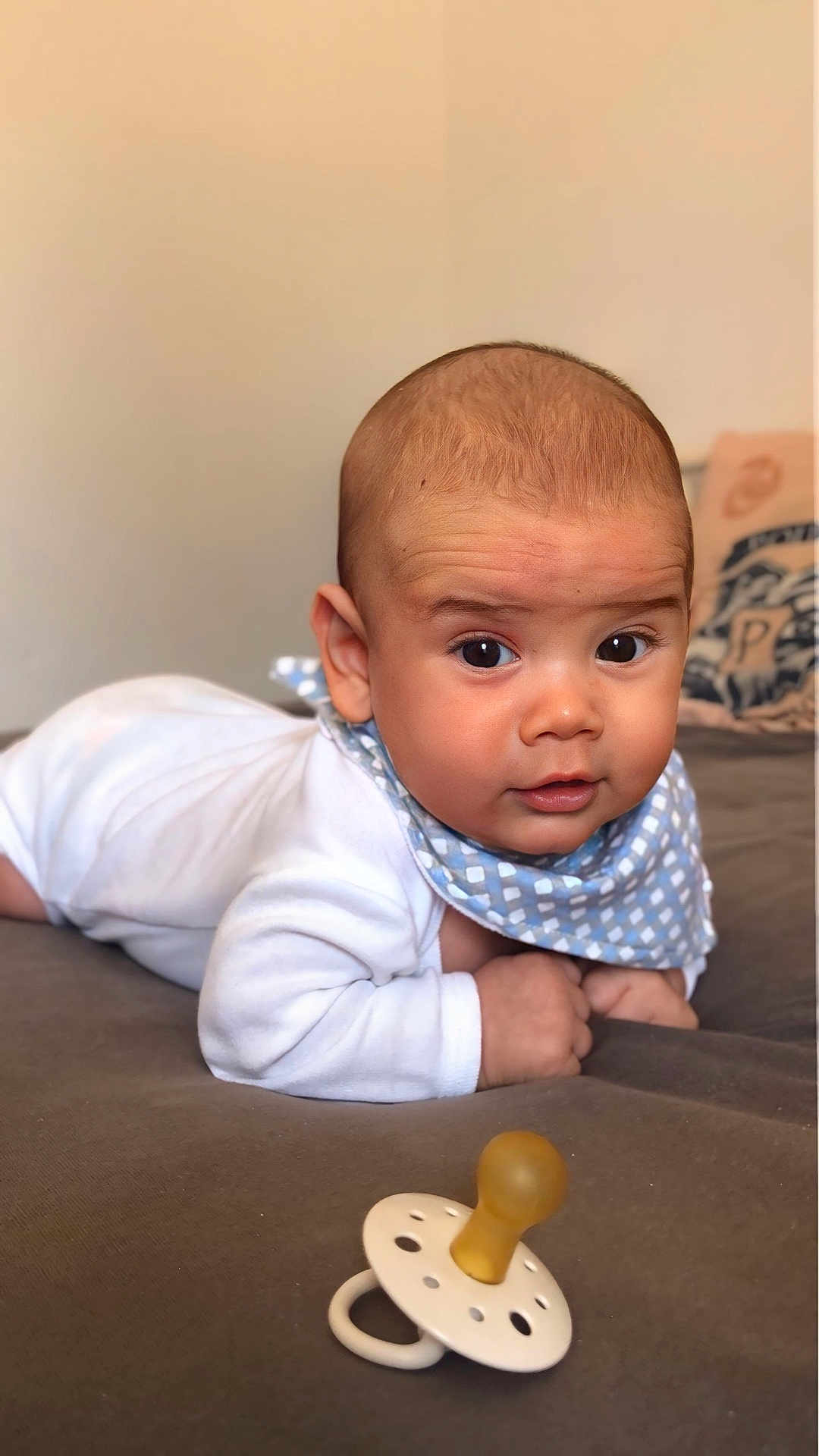 Damian participe au concours pour gagner de l'argent avec cette photo : baby, infant, pacifier, white_clothing, bib, bed, face, expression, cute, lying_down, skin, head, hands, indoor, soft_surface, closeup, portrait, child, young, curious