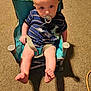 baby, pacifier, child, chair, striped_clothing, blue_clothing, dinosaur_patch, carpet, indoor, dog_paws, small_chair, seated, looking_up, curious, infant, cute, legs, feet, shadow, comfort