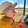 Matthew joined the competition — help win amazing prizes! toddler, child, hat, straw_hat, yellow_hoodie, smiling, side_profile, outdoor, park, picnic_table, toy, daylight, happy, face, person, sunny, background_blur, hand, sippy_cup, casual_clothing