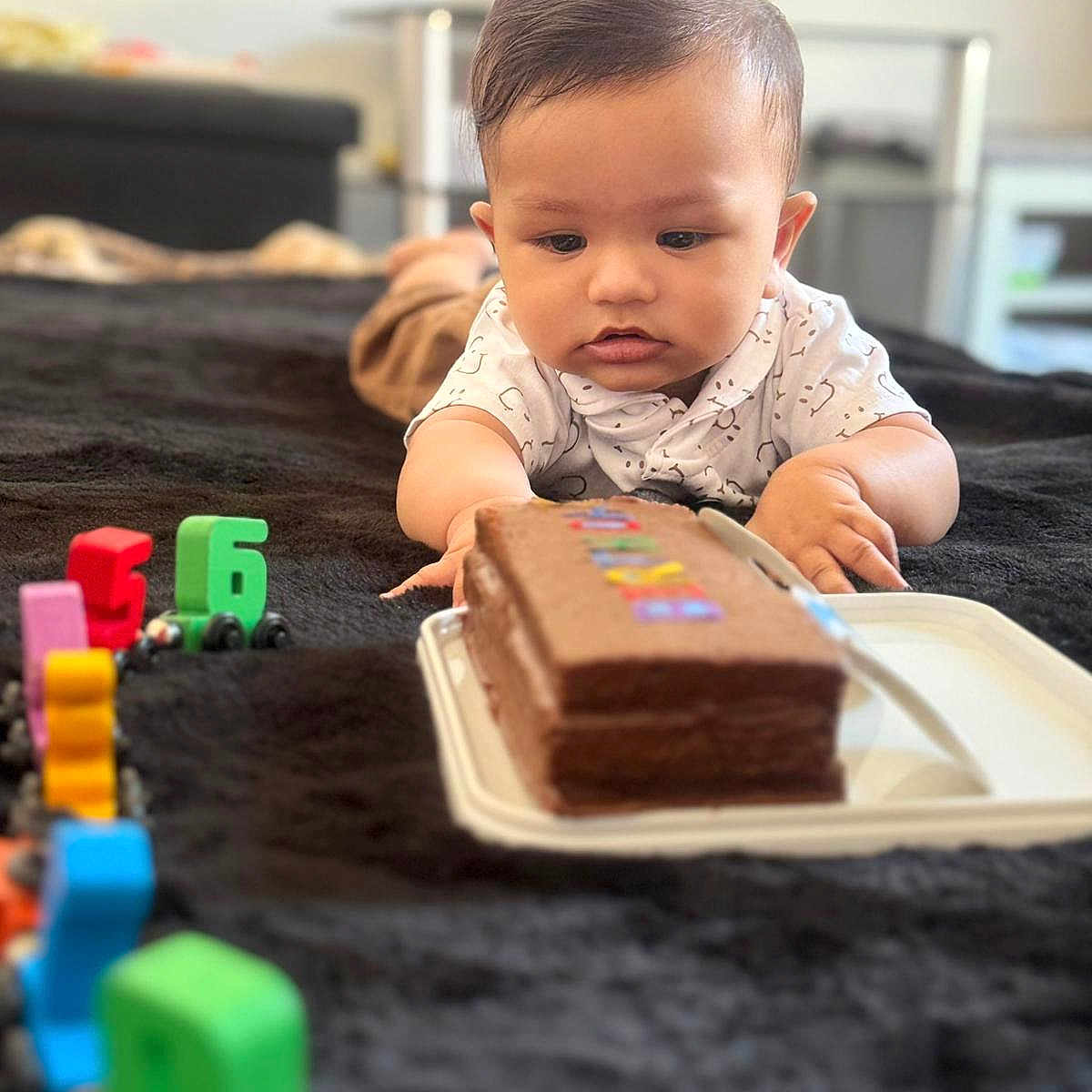 Aadhvin joined the competition — help win amazing prizes! baby, blanket, cake, casual_clothing, child, chocolate, colorful, curious, focus, food, furniture, indoor, lying_down, numbers, play, room, soft_texture, table, toy, young_child