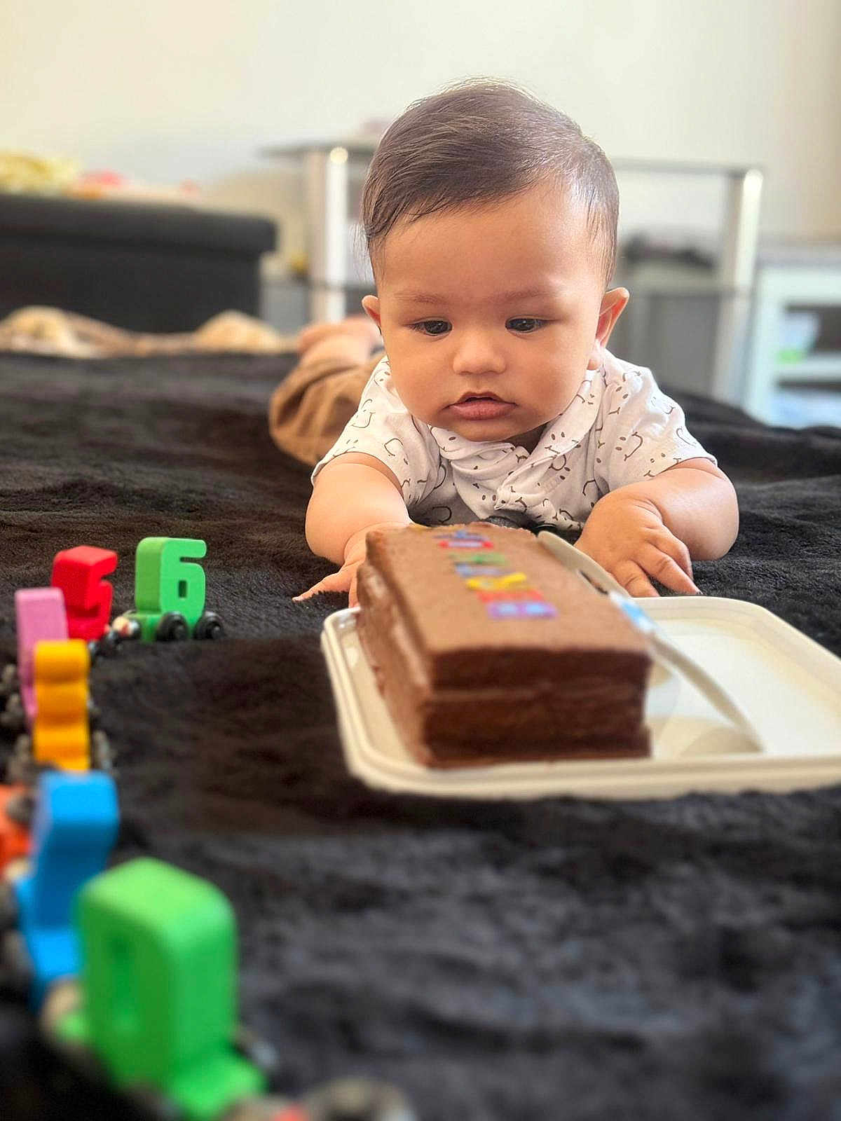 Aadhvin joined the competition — help win amazing prizes! baby, child, cake, toy, numbers, blanket, indoor, curious, lying_down, focus, colorful, chocolate, food, play, young_child, soft_texture, room, furniture, table, casual_clothing