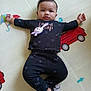Aadhvin is registered to the contest to win money with this photo: baby, child, infant, black_clothing, toy, play_mat, colorful, elephant, umbrella, vehicle, lying_down, arms_outstretched, footwear, cute, indoors, floor_mat, patterned_clothing, smiling_face, young_child, portrait