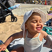 Ambre participe au concours pour gagner de l'argent avec cette photo : baby, child, beach, sand, sun_hat, tank_top, playing, smiling, sunlight, outdoor, towel, stroller, summer, happy, cute, earrings, tongue_out, sitting, daytime, vacation