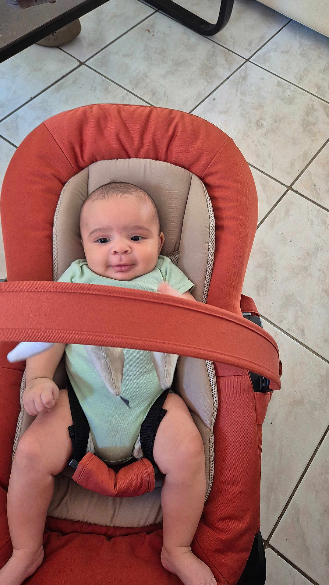 Jaël a rejoint le concours — aidez-le/la à gagner de superbes lots ! baby, baby_carrier, baby_clothing, baby_expression, baby_face, baby_gesture, baby_hands, baby_legs, baby_pose, baby_rocker, baby_safety, baby_seat, baby_smile, child, floor_tiles, indoor, infant, onesie, seatbelt, tiled_floor