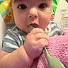 baby, infant, spoon, blanket, close_up, face, hand, curious, indoor, striped_clothing, pink, green, child, young, person, candid, feeding, expression, cute, portrait