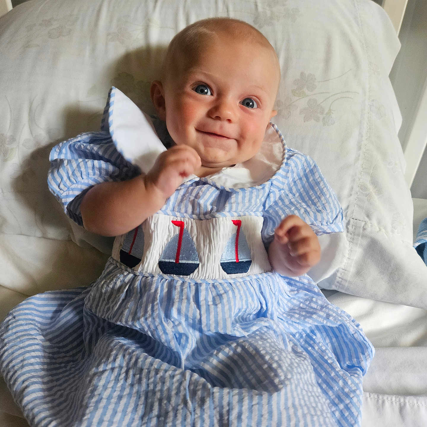 Atillia joined the competition — help win amazing prizes! baby, bed, blue_dress, child, clothing, crib, cute, face, happy, head, human, indoor, infant, person, pillow, portrait, sailboat_embroidery, sitting, smiling, striped_dress