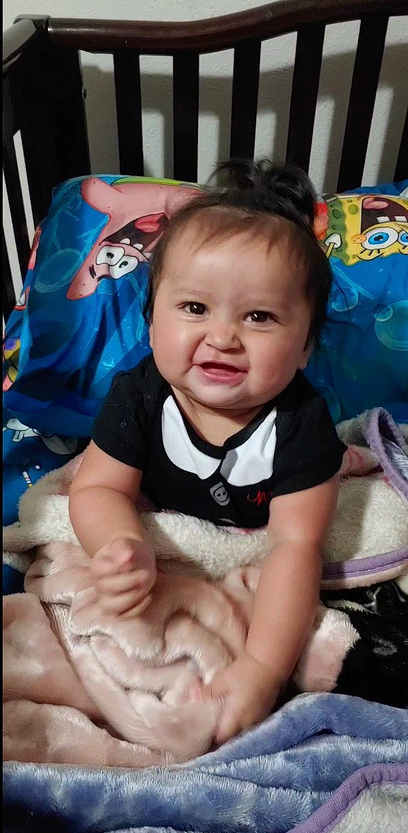 Leia joined the competition — help win amazing prizes! baby, baby_products, baby_toddler_clothing, cheek, child, eye, facial_expression, fun, gesture, happy, iris, linens, pattern, person, room, sitting, skin, sleeve, smile, t_shirt