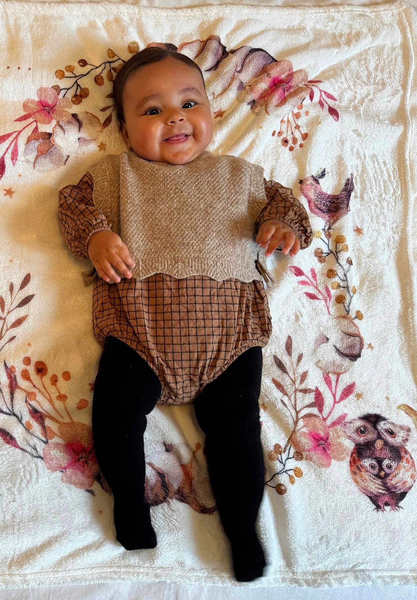 Jannah participe au concours pour gagner de l'argent avec cette photo : baby, smiling, infant, blanket, floral_pattern, clothing, knitted_vest, tights, cute, happy, portrait, child, laying_down, indoors, soft_texture, face, hands, legs, fashion, warm