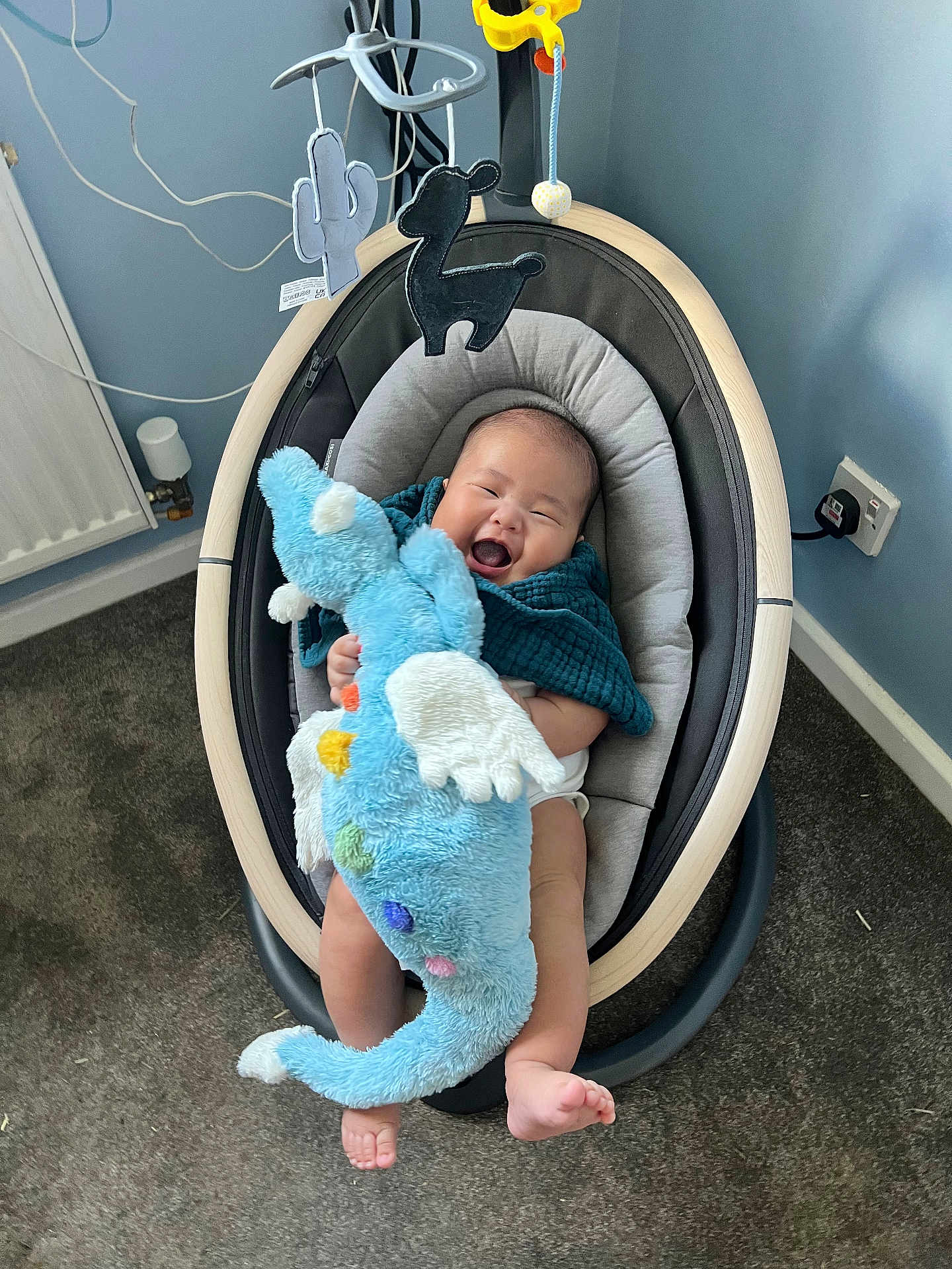 Jenson joined the competition — help win amazing prizes! baby, infant, smiling, plush_toy, baby_rocker, blanket, carpet, indoor, child, happy, person, foot, hand, wall, power_outlet, toy, blue, fabric, seat, cute