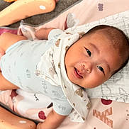 Jenson is registered to the contest to win money with this photo: baby, child, smiling, lying_down, play_mat, blanket, bib, toy, indoor, cute, happy, infant, person, head, face, soft_toys, colorful, clothing, closeup, young