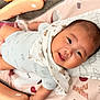 baby, child, smiling, lying_down, play_mat, blanket, bib, toy, indoor, cute, happy, infant, person, head, face, soft_toys, colorful, clothing, closeup, young