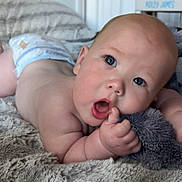 Ridley is registered to the contest to win money with this photo: baby, infant, diaper, blanket, plush_toy, hand, face, skin, mouth, eye, indoor, curious, soft_texture, lying_down, close_up, cute, child, toddler, newborn, expression