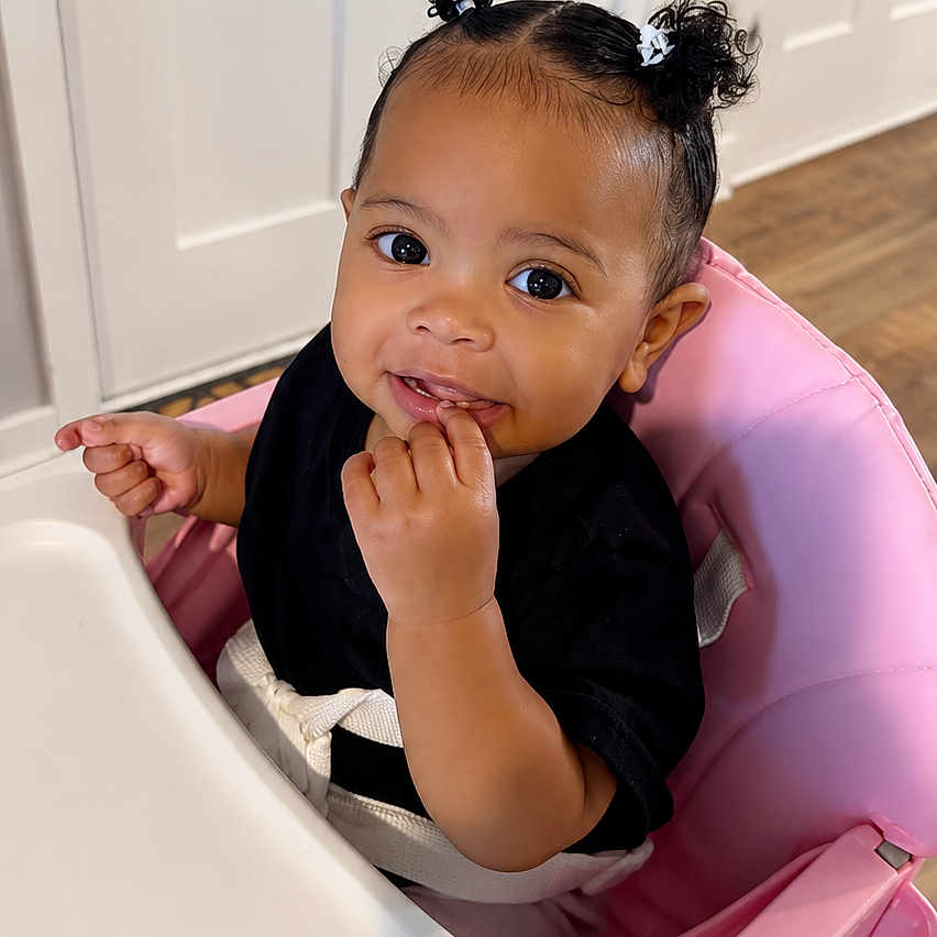 Favor joined the competition — help win amazing prizes! baby, black_shirt, cabinet, child, curly_hair, cute, feeding_chair, hair_bows, happy, high_chair, indoor, kitchen, person, pink, portrait, seatbelt, smiling, toddler, wood_floor, young_child