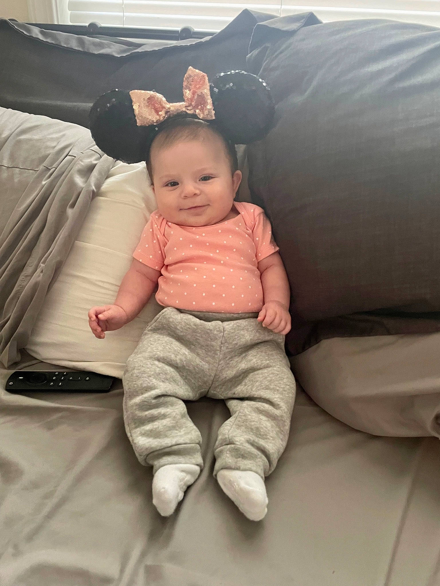 Paisley is registered to the contest to win money with this photo: arm, baby, baby_toddler_clothing, cheek, child, comfort, couch, eye, finger, happy, head, human_body, joy, leg, person, sitting, skin, sleeve, smile, t_shirt