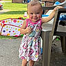 Wrenley is registered to the contest to win money with this photo: backyard, barefoot, chair, child, colorful_clothing, concrete, daylight, dress, face, grass, hairstyle, house, mohawk, outdoor, patio, person, playpen, smile, toddler, toy