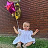 baby, balloons, birthday, brick_wall, celebration, child, cute, daylight, event, festive, grass, outdoor, person, playful, portrait, shoes, sitting, toddler, white_dress, young_child