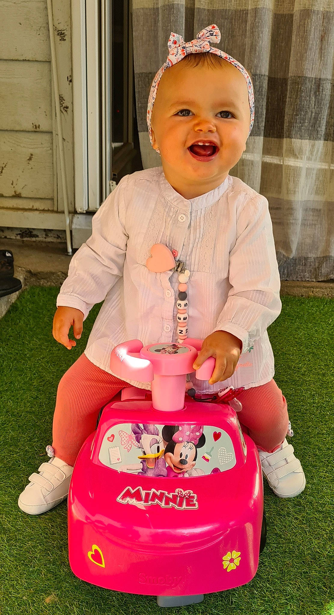 Inès a rejoint le concours — aidez-le/la à gagner de superbes lots ! baby, baby_playing_with_toys, baby_products, baby_toddler_clothing, cabinetry, child, facial_expression, fun, grass, green, happy, person, pink, recreation, riding_toy, shorts, sitting, smile, toddler, white
