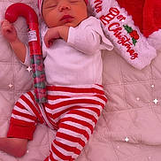 Iñaki is registered to the contest to win money with this photo: baby, sleeping, christmas, holiday, festive, red_and_white, striped_clothing, hat, candy_cane, candy, quilted_blanket, santa_hat, infant, cute, peaceful, bed, pajamas, celebration, cozy, sparkles