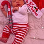 baby, sleeping, christmas, holiday, festive, red_and_white, striped_clothing, hat, candy_cane, candy, quilted_blanket, santa_hat, infant, cute, peaceful, bed, pajamas, celebration, cozy, sparkles